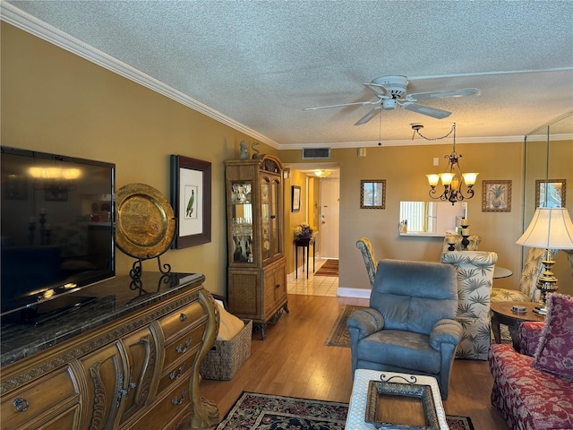 living room featuring a textured ceiling, ornamental molding, ceiling fan with notable chandelier, and light wood-type flooring