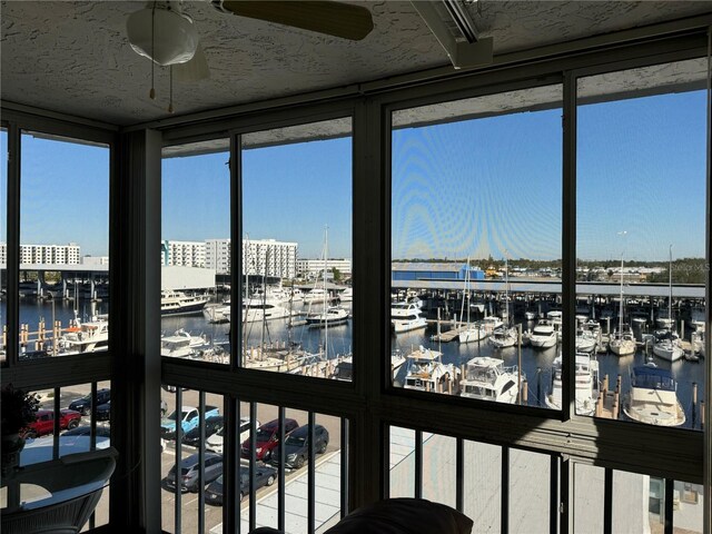 sunroom / solarium featuring ceiling fan and a water view