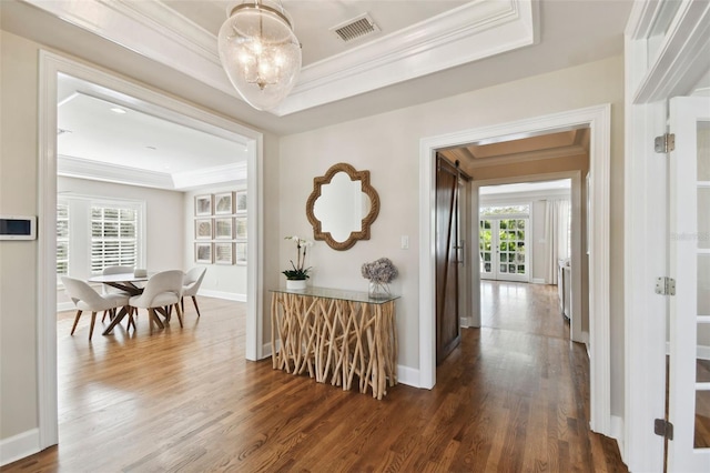 corridor featuring a raised ceiling, crown molding, dark hardwood / wood-style flooring, and a chandelier