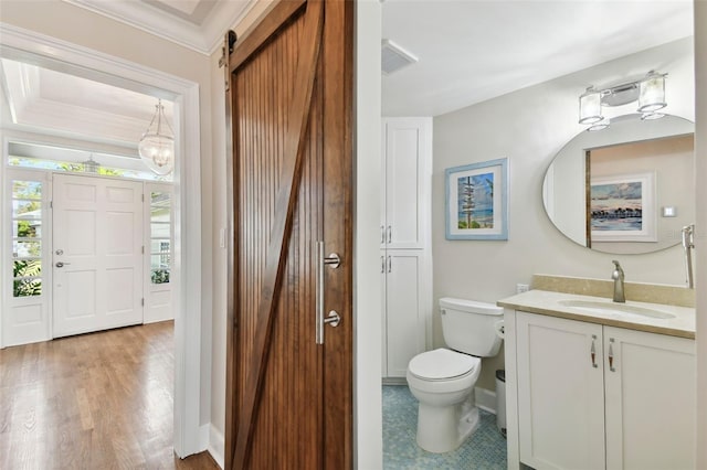 bathroom featuring vanity, toilet, wood-type flooring, and ornamental molding