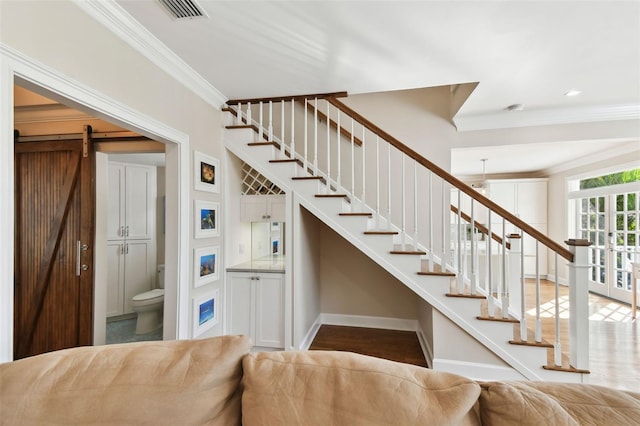 stairs featuring hardwood / wood-style flooring, a barn door, and ornamental molding