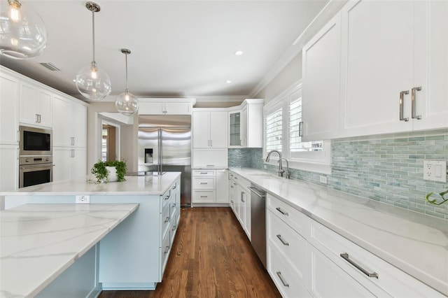 kitchen featuring dark wood-type flooring, sink, built in appliances, white cabinets, and hanging light fixtures