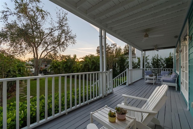 deck at dusk featuring ceiling fan and a yard