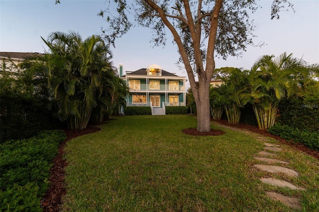 view of front facade featuring a balcony and a lawn