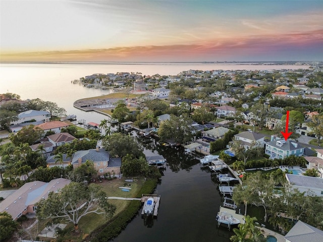 aerial view at dusk featuring a water view