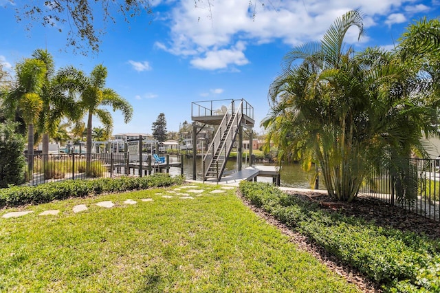 view of yard featuring a water view, a dock, and fence