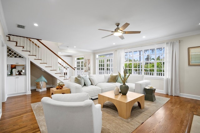 living room with ornamental molding, wood finished floors, and stairs