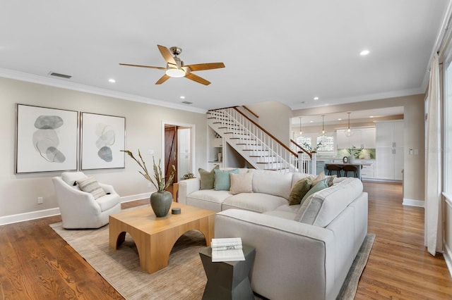 living area with light wood-type flooring, stairway, and ornamental molding