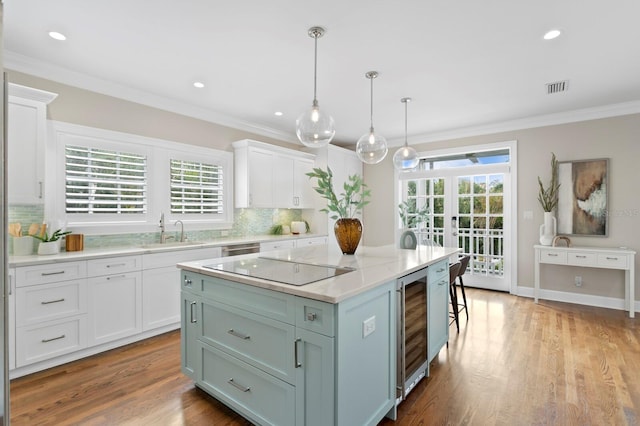 kitchen with a center island, decorative light fixtures, white cabinetry, a sink, and black electric cooktop