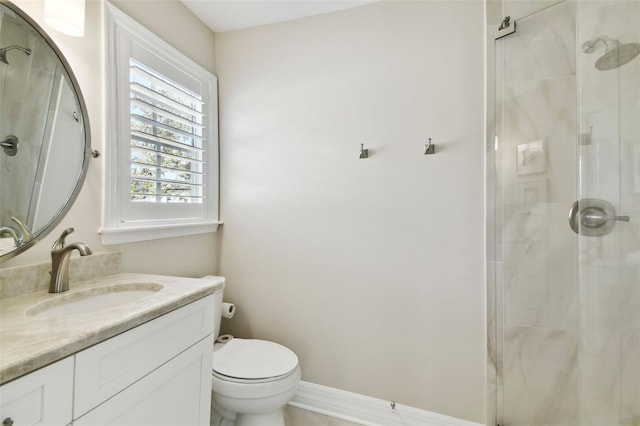 bathroom with toilet, a shower stall, baseboards, and vanity