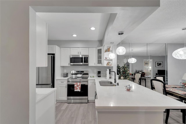 kitchen with white cabinetry, hanging light fixtures, stainless steel appliances, and light wood-type flooring