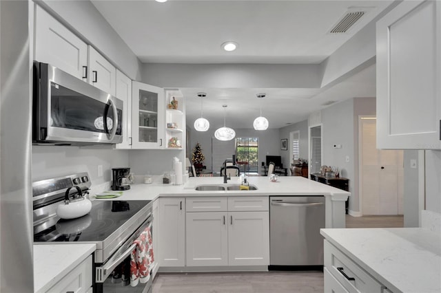 kitchen with kitchen peninsula, appliances with stainless steel finishes, sink, light hardwood / wood-style flooring, and white cabinetry