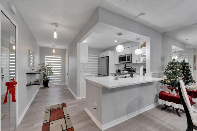 kitchen featuring a textured ceiling, white cabinetry, kitchen peninsula, and stainless steel appliances