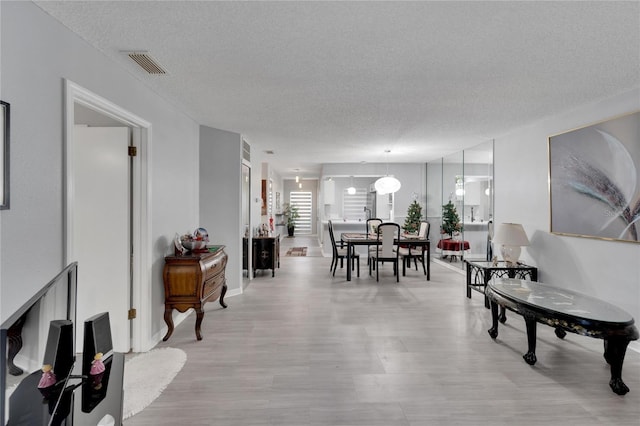 dining space featuring light hardwood / wood-style flooring and a textured ceiling