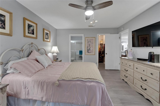 bedroom featuring ceiling fan, a spacious closet, light hardwood / wood-style flooring, ensuite bathroom, and a closet