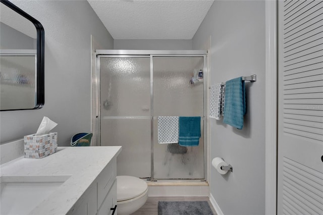 bathroom featuring vanity, a textured ceiling, toilet, and an enclosed shower