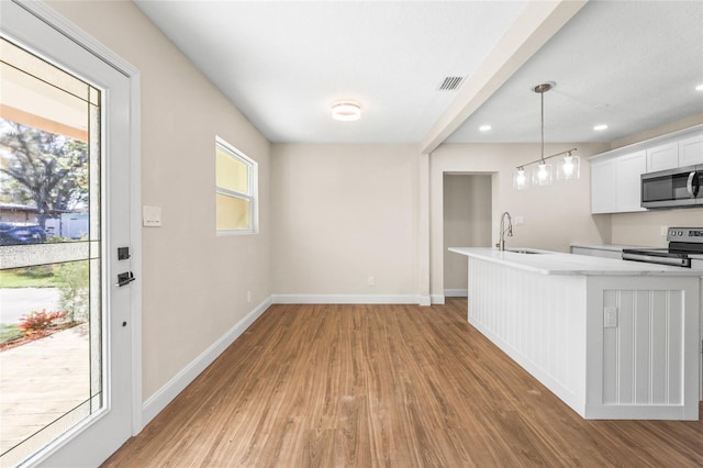 kitchen with decorative light fixtures, a healthy amount of sunlight, stainless steel appliances, and white cabinetry