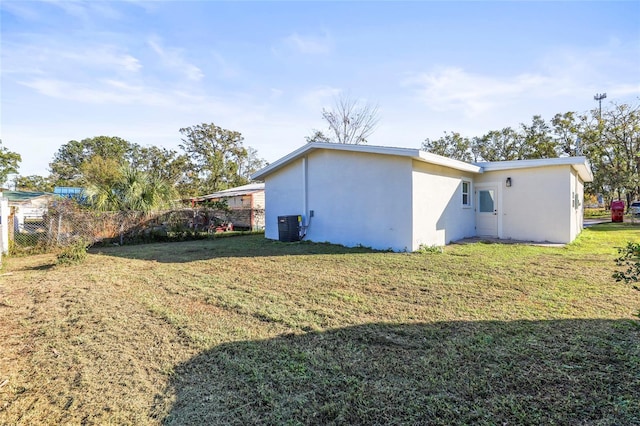 back of property with central air condition unit and a lawn