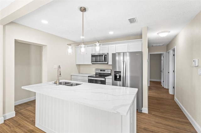 kitchen featuring white cabinets, appliances with stainless steel finishes, an island with sink, sink, and light stone counters