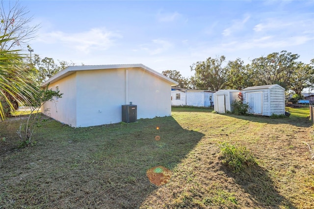 view of side of property with a storage shed, a yard, and central AC