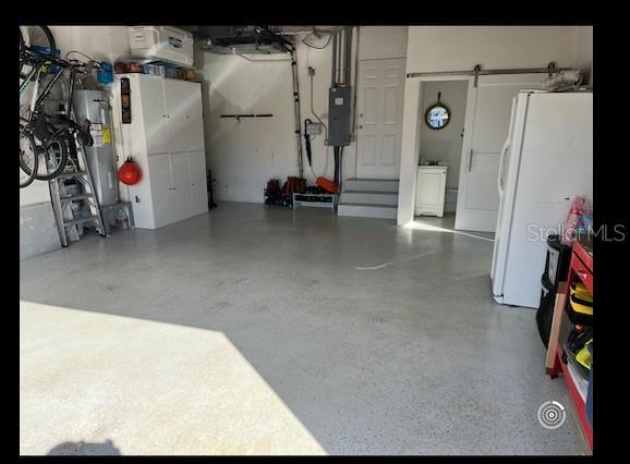 garage with freestanding refrigerator, electric panel, and water heater