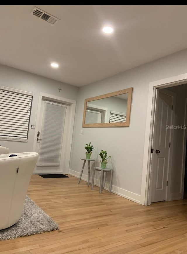 corridor featuring light wood finished floors, recessed lighting, visible vents, and baseboards