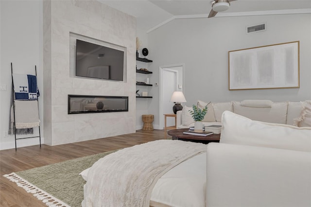 living room featuring built in shelves, a tile fireplace, ceiling fan, hardwood / wood-style floors, and lofted ceiling