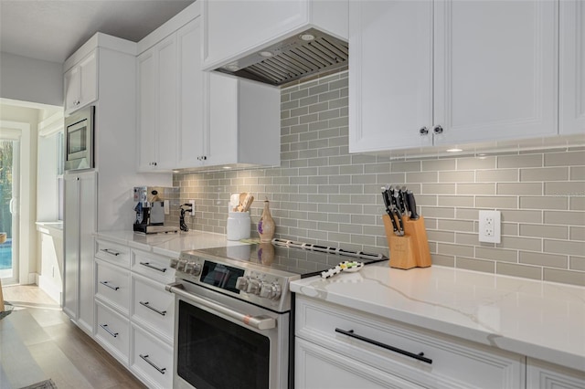 kitchen with custom exhaust hood, backsplash, white cabinets, light stone countertops, and stainless steel appliances