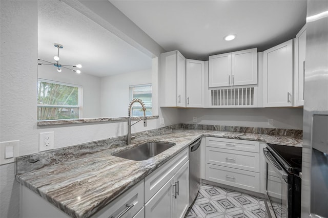 kitchen featuring kitchen peninsula, light stone counters, sink, dishwasher, and white cabinetry