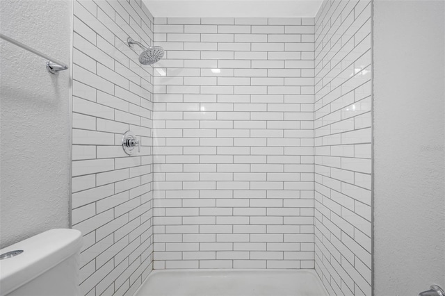 bathroom with a tile shower and toilet