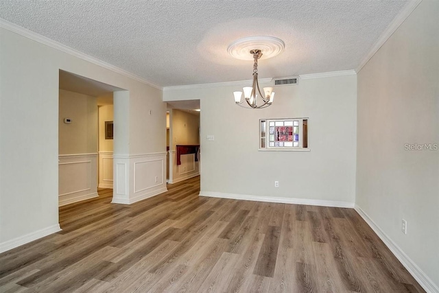 unfurnished dining area featuring ornamental molding, hardwood / wood-style floors, a textured ceiling, and an inviting chandelier