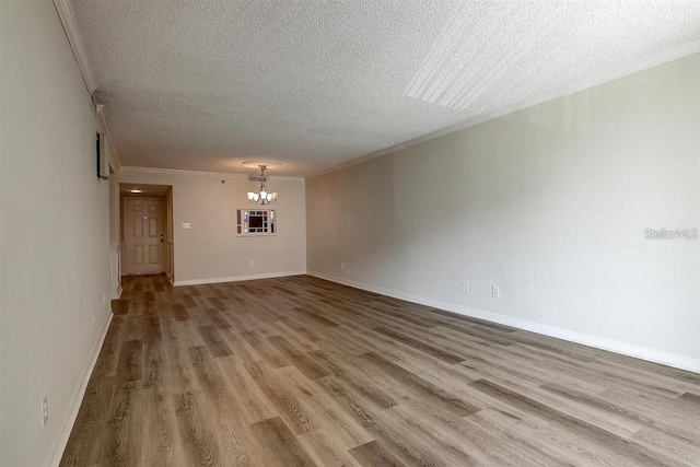 interior space with hardwood / wood-style flooring, ornamental molding, a textured ceiling, and a chandelier