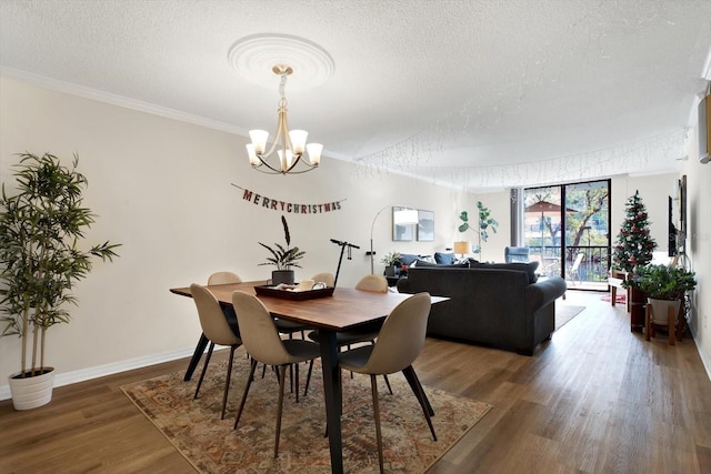 dining area featuring a notable chandelier, crown molding, dark wood-type flooring, and a textured ceiling