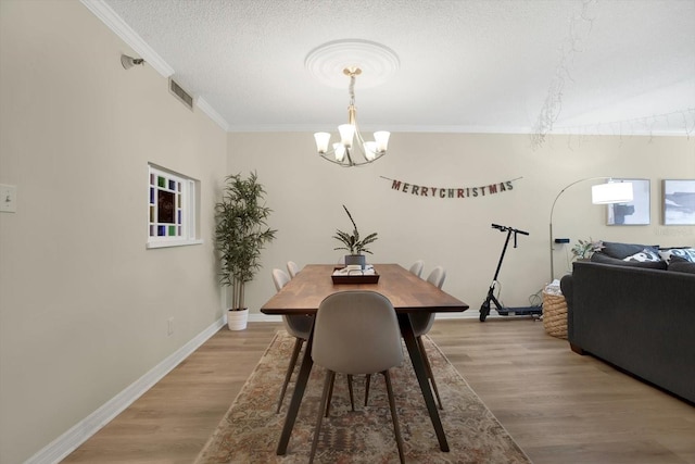 dining area with a notable chandelier, crown molding, light hardwood / wood-style flooring, and a textured ceiling