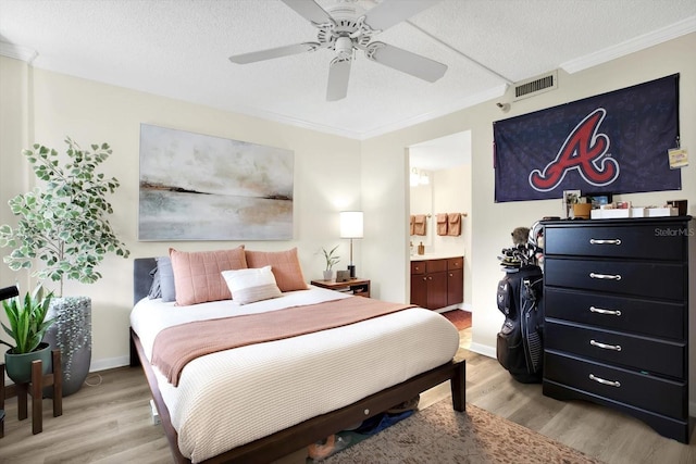 bedroom with crown molding, connected bathroom, light hardwood / wood-style floors, and a textured ceiling