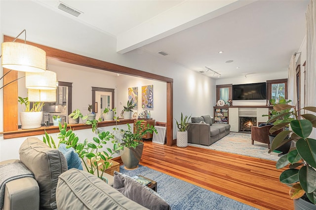 living room with hardwood / wood-style floors, a fireplace, and beamed ceiling