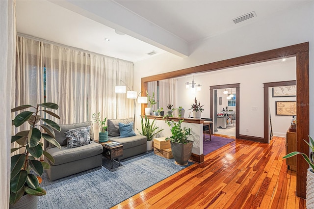 living room with a chandelier, beamed ceiling, and wood-type flooring