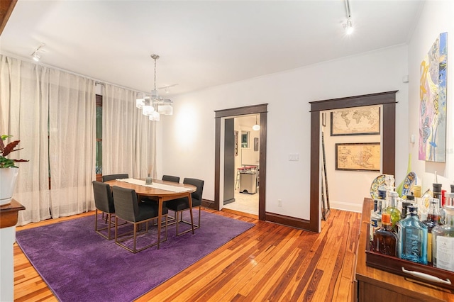 dining space with hardwood / wood-style flooring, a notable chandelier, and rail lighting