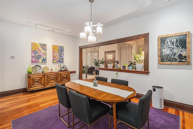 dining space featuring a notable chandelier, track lighting, and hardwood / wood-style flooring