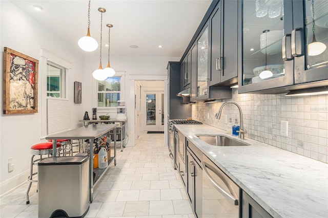 kitchen featuring tasteful backsplash, light stone counters, stainless steel appliances, sink, and hanging light fixtures