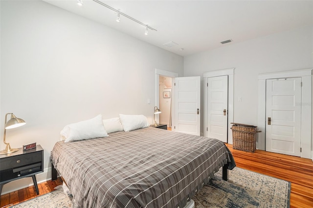 bedroom featuring hardwood / wood-style floors and rail lighting