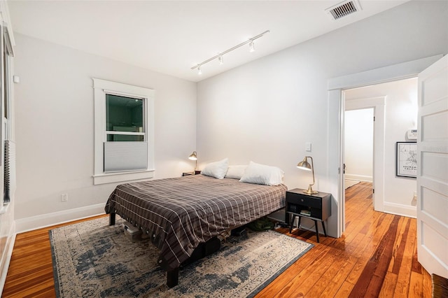 bedroom featuring hardwood / wood-style floors and rail lighting