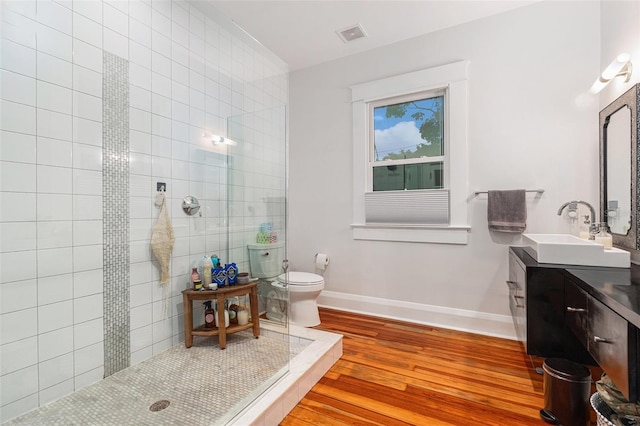 bathroom featuring tiled shower, wood-type flooring, vanity, and toilet