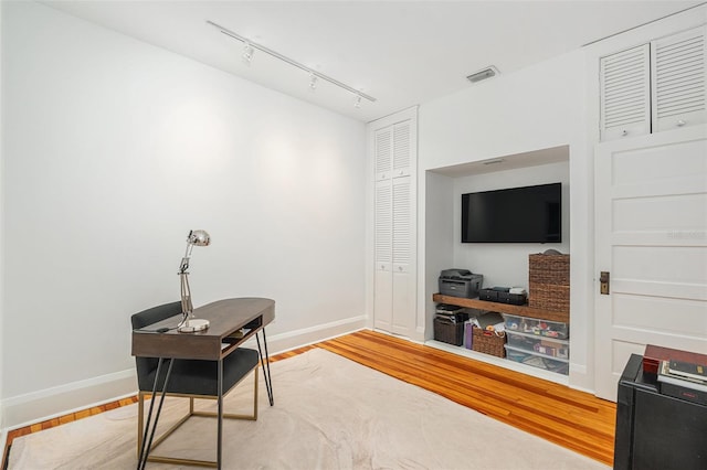 home office featuring wood-type flooring and track lighting