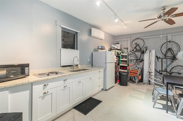 kitchen with a wall mounted air conditioner, light stone countertops, sink, white cabinets, and white fridge