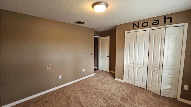 unfurnished bedroom featuring light colored carpet, a textured ceiling, and a closet