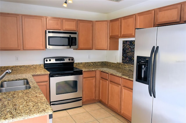 kitchen featuring light stone counters, stainless steel appliances, and sink