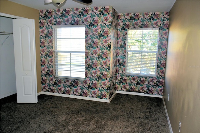 unfurnished bedroom with dark carpet and ceiling fan