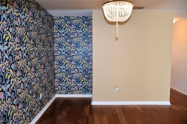 unfurnished room featuring dark hardwood / wood-style flooring and an inviting chandelier