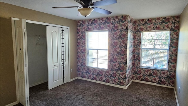 unfurnished bedroom with dark carpet, a closet, and ceiling fan